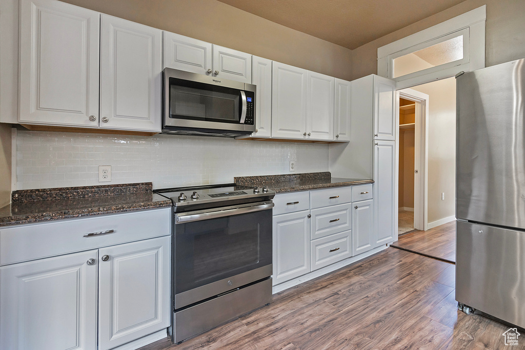 Kitchen featuring appliances with stainless steel finishes, white cabinetry, and hardwood / wood-style floors