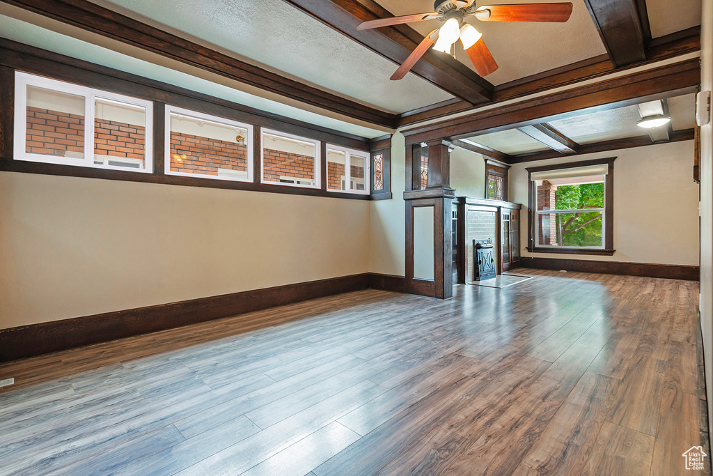 Interior space with dark wood-type flooring, ornamental molding, ceiling fan, and a brick fireplace