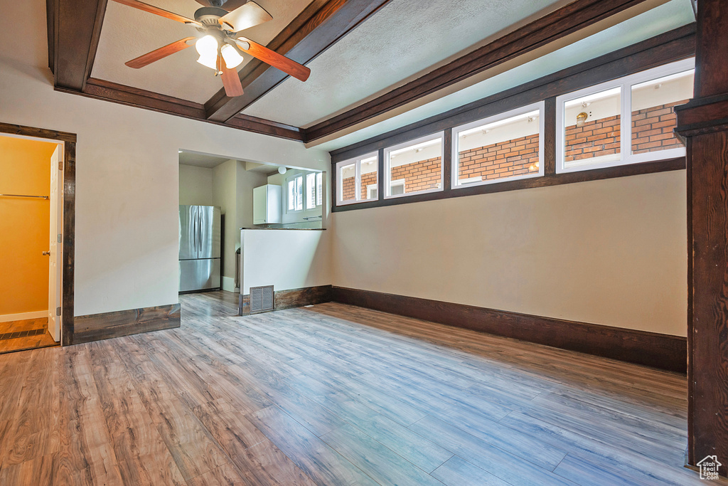 Unfurnished room featuring crown molding, beamed ceiling, ceiling fan, and hardwood / wood-style floors