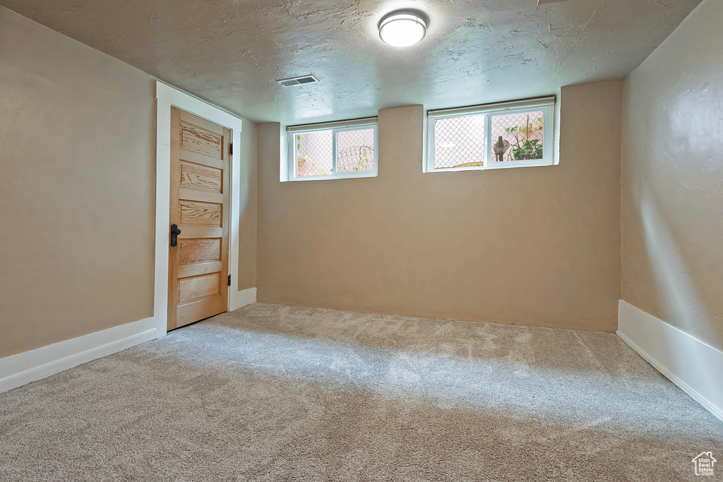 Basement with a textured ceiling and carpet