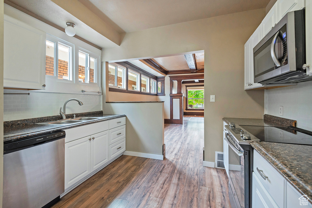 Kitchen featuring sink, wood-type flooring, white cabinetry, and appliances with stainless steel finishes