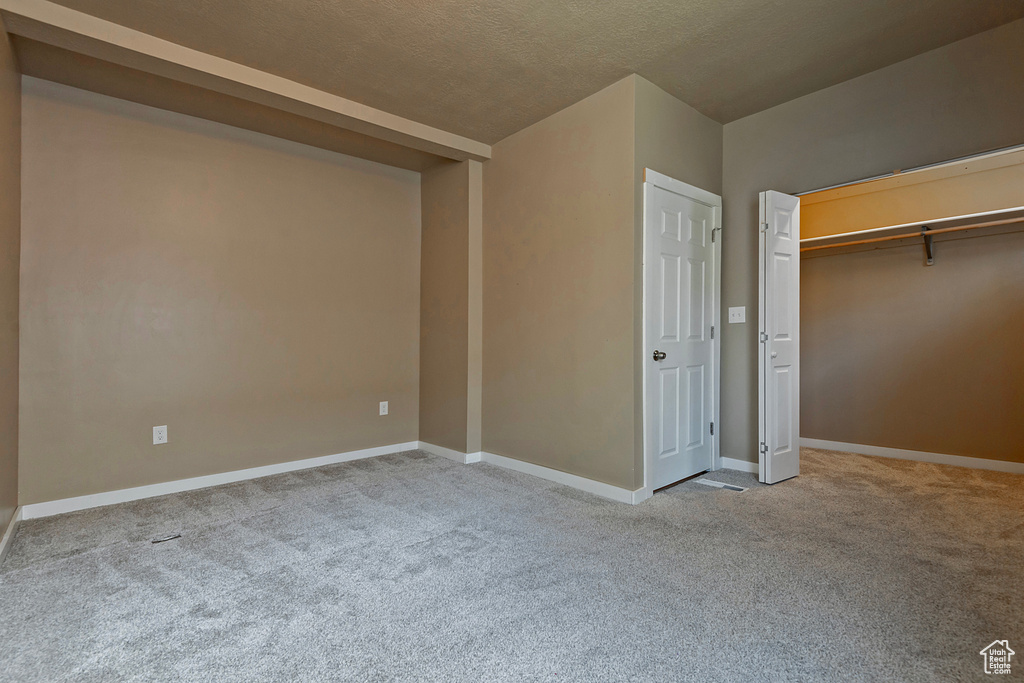 Unfurnished bedroom with a closet, a textured ceiling, and carpet floors