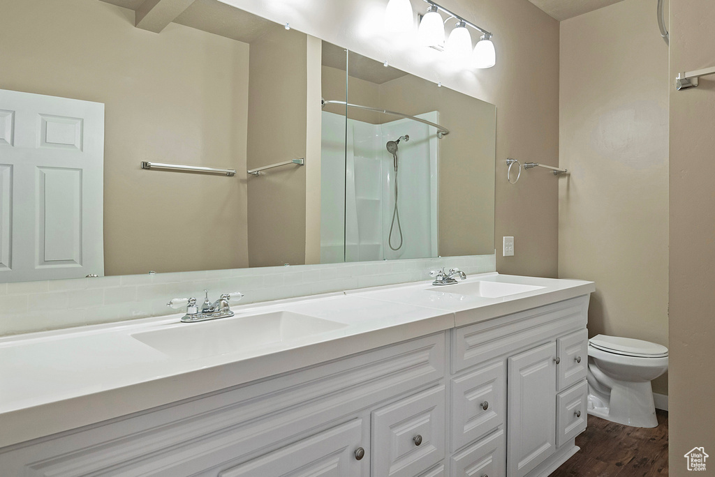 Bathroom with a shower, toilet, double sink vanity, and hardwood / wood-style floors