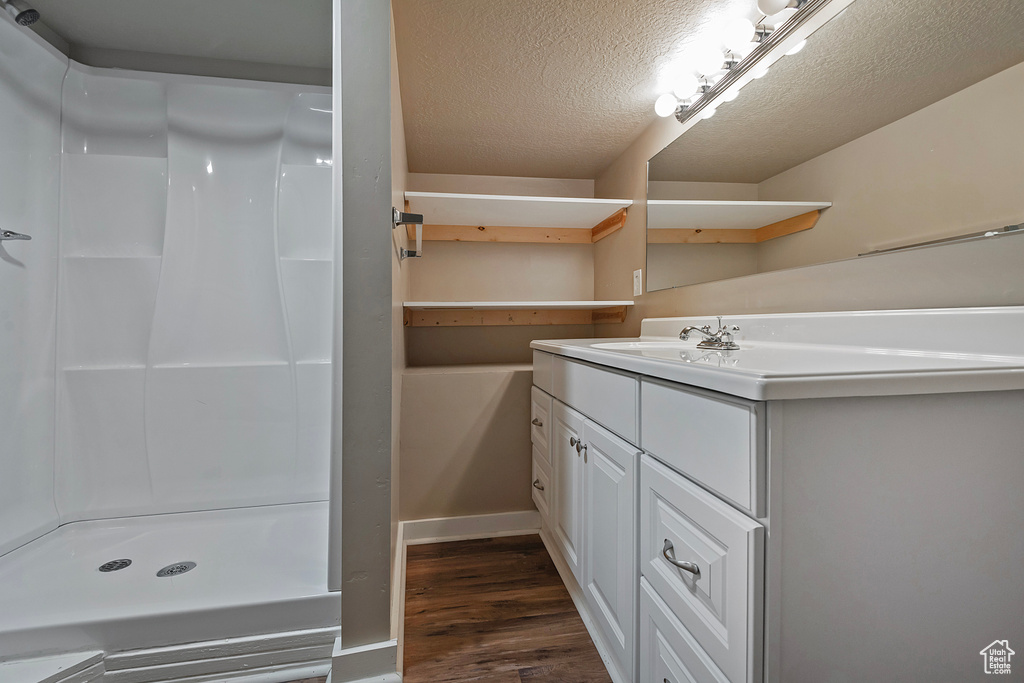 Bathroom with a textured ceiling, a shower, oversized vanity, and hardwood / wood-style floors