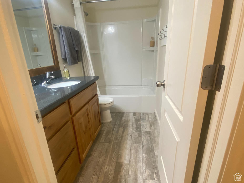 Full bathroom with hardwood / wood-style floors, vanity, toilet, and bathing tub / shower combination