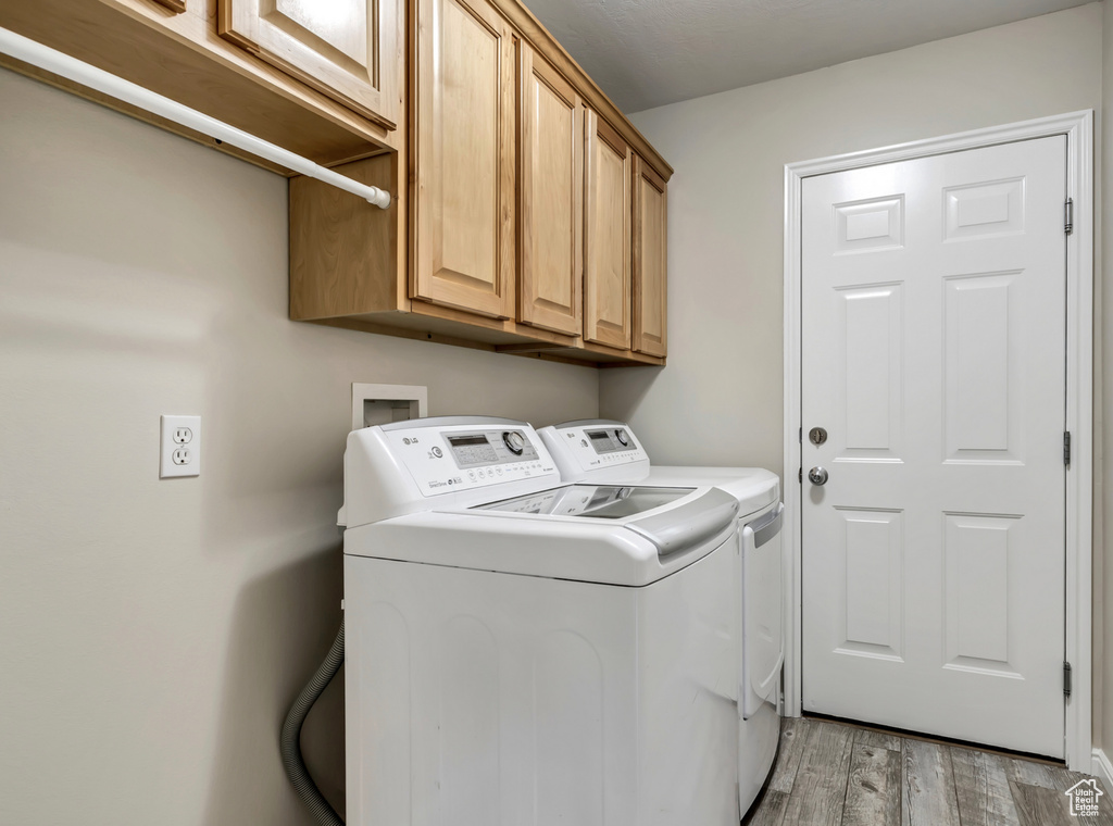 Clothes washing area featuring cabinets, washer hookup, hardwood / wood-style flooring, and washing machine and dryer