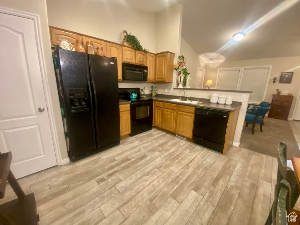 Kitchen with sink, black appliances, light wood-type flooring, and kitchen peninsula