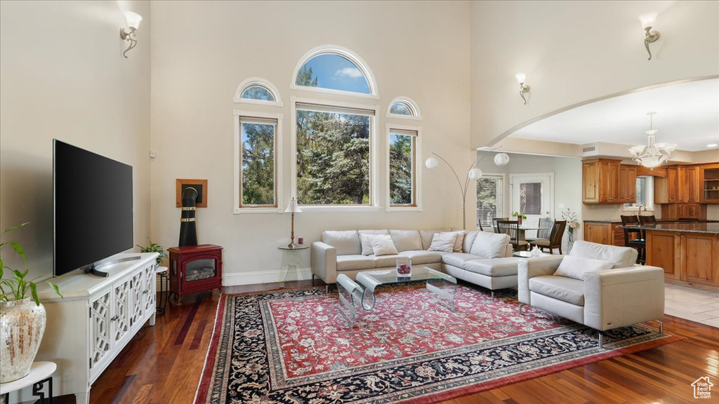 Living room with a towering ceiling, an inviting chandelier, and dark hardwood / wood-style flooring