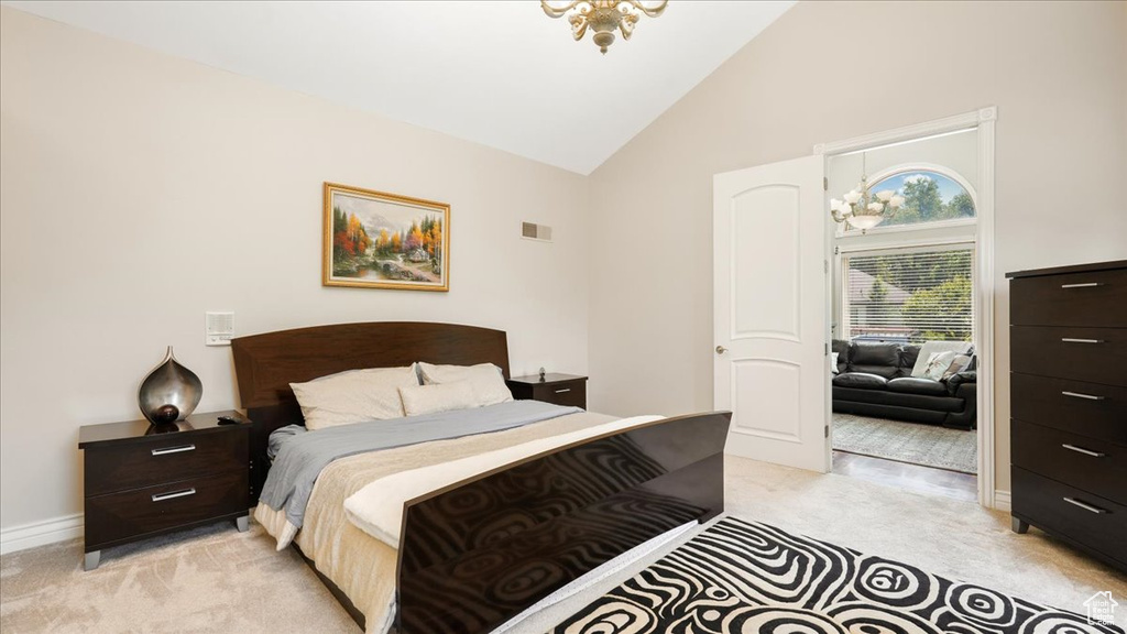 Bedroom featuring light carpet, high vaulted ceiling, and an inviting chandelier