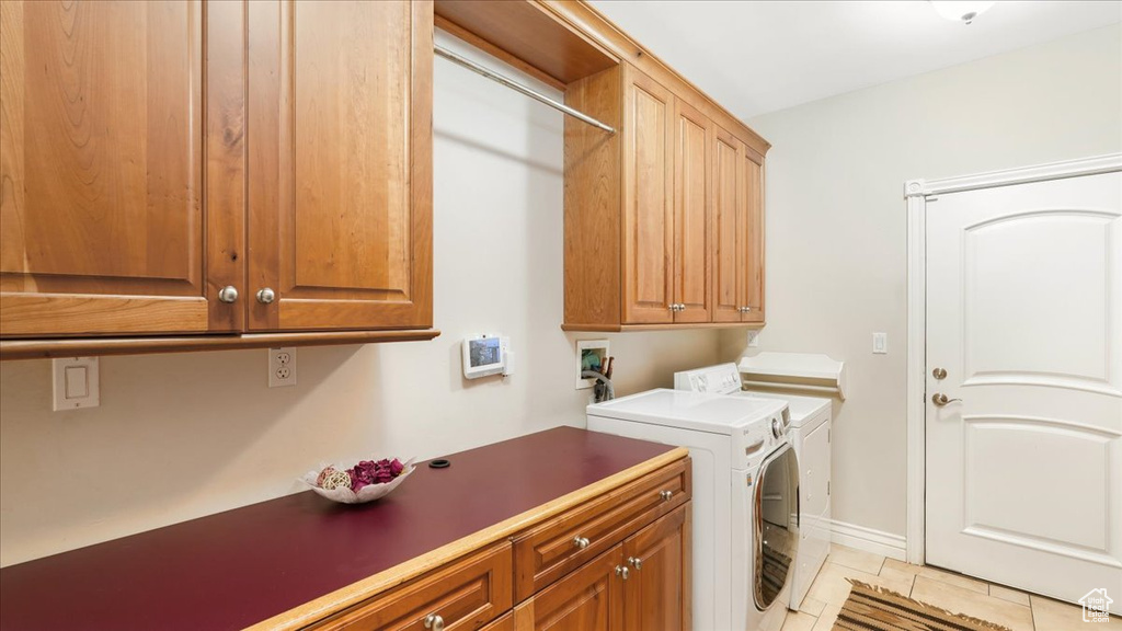 Laundry room with cabinets, separate washer and dryer, light tile floors, and washer hookup