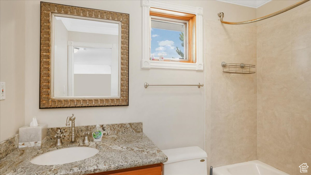 Full bathroom featuring tiled shower / bath combo, toilet, and vanity with extensive cabinet space