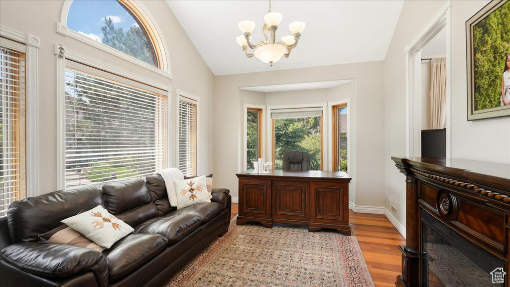 Living room featuring vaulted ceiling, a chandelier, and light hardwood / wood-style flooring