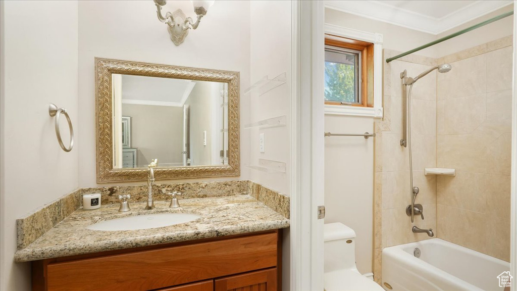 Full bathroom with tiled shower / bath combo, ornamental molding, vanity, and toilet