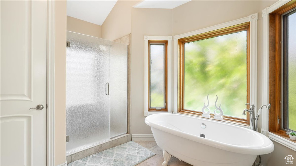 Bathroom with plenty of natural light, separate shower and tub, tile floors, and lofted ceiling