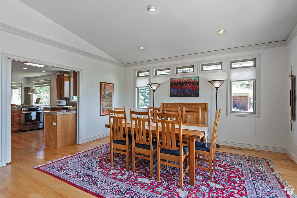 Dining room with ornamental molding, light hardwood / wood-style flooring, and lofted ceiling