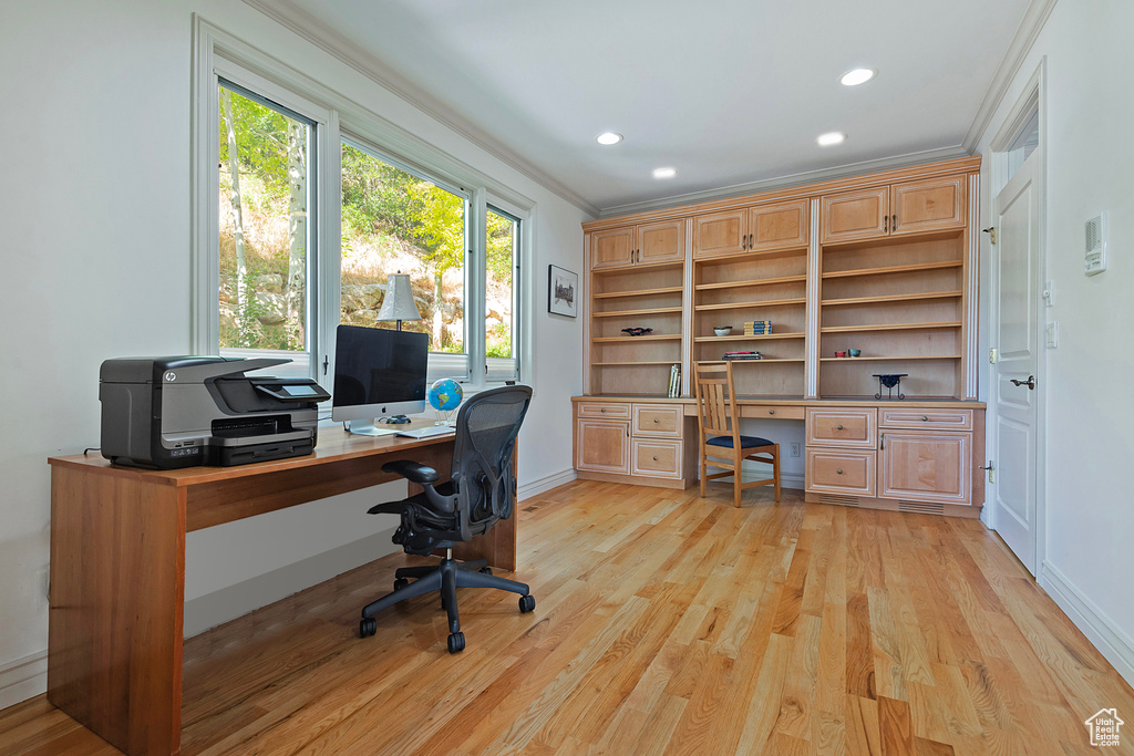 Office featuring built in desk, ornamental molding, and light wood-type flooring