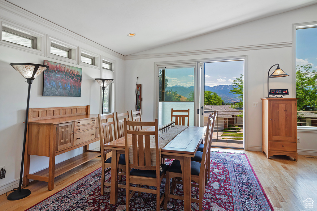 Dining area featuring a wealth of natural light, wood-type flooring, and vaulted ceiling