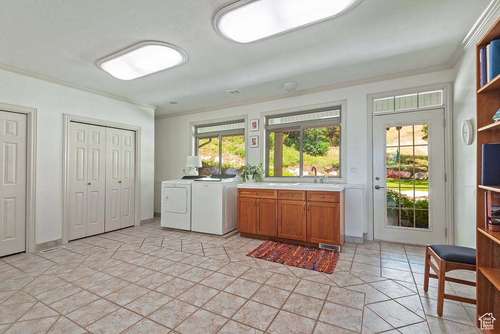 Kitchen featuring ornamental molding, washer and dryer, light tile flooring, and sink