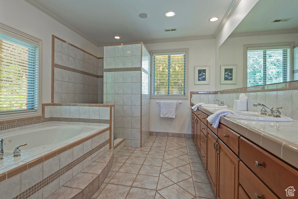 Bathroom with tile flooring, dual vanity, tiled bath, and ornamental molding