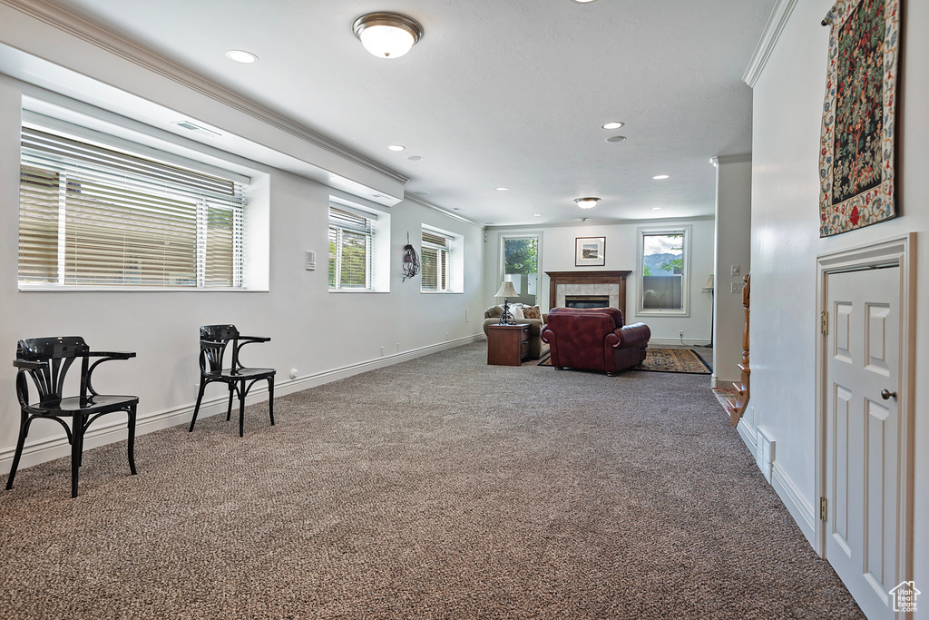 Living area featuring carpet, a tile fireplace, and crown molding