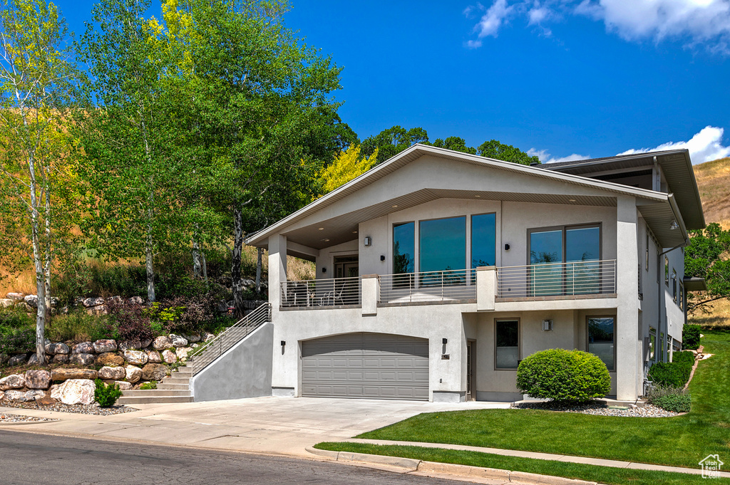 Contemporary home featuring a garage, a front yard, and a balcony