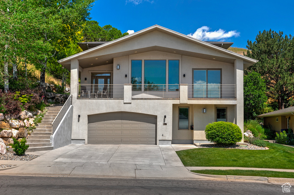 Contemporary house with a garage, a front lawn, and a balcony