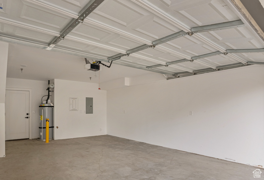 Garage featuring a garage door opener, electric panel, and water heater