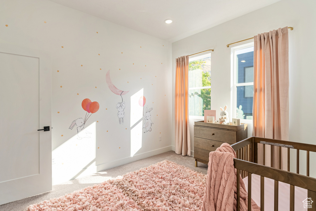 Carpeted bedroom featuring a crib