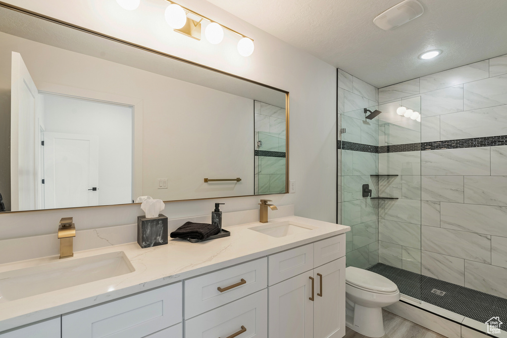 Bathroom with vanity, toilet, hardwood / wood-style flooring, and an enclosed shower