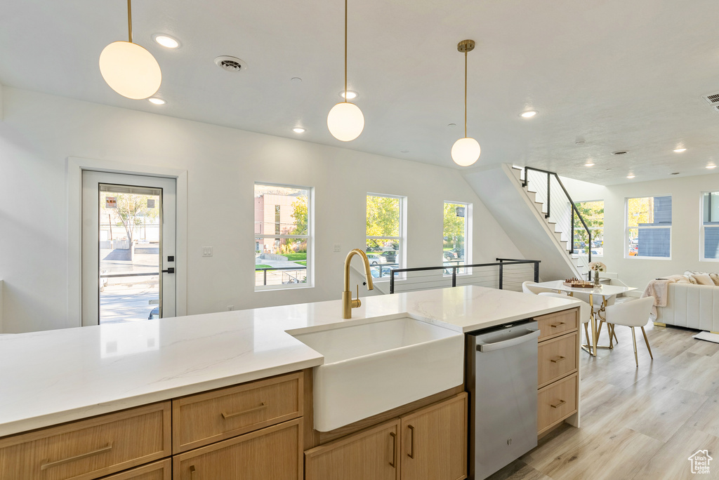 Kitchen with sink, light wood-type flooring, decorative light fixtures, and stainless steel dishwasher