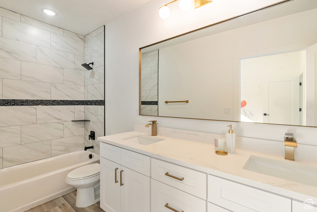 Full bathroom with vanity, toilet, wood-type flooring, and tiled shower / bath