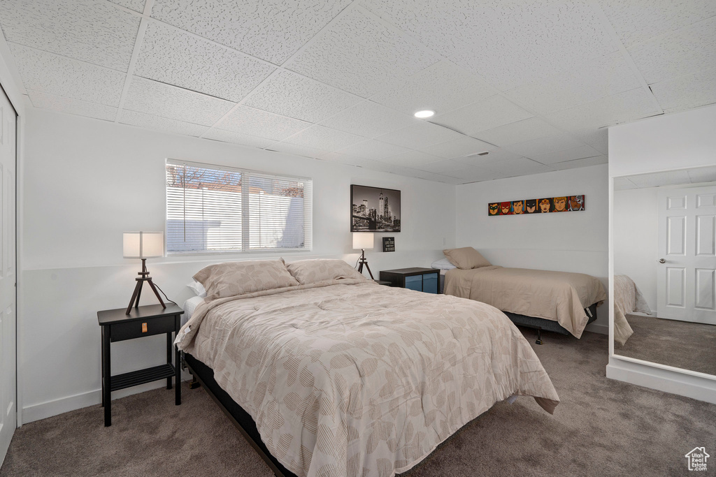 Bedroom featuring a paneled ceiling and dark colored carpet