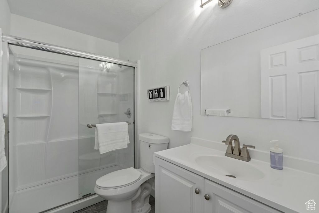 Bathroom with a shower with door, oversized vanity, and toilet