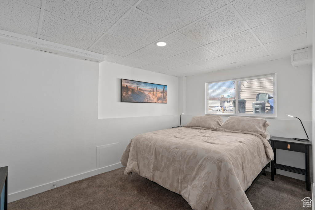 Carpeted bedroom with a drop ceiling and an AC wall unit