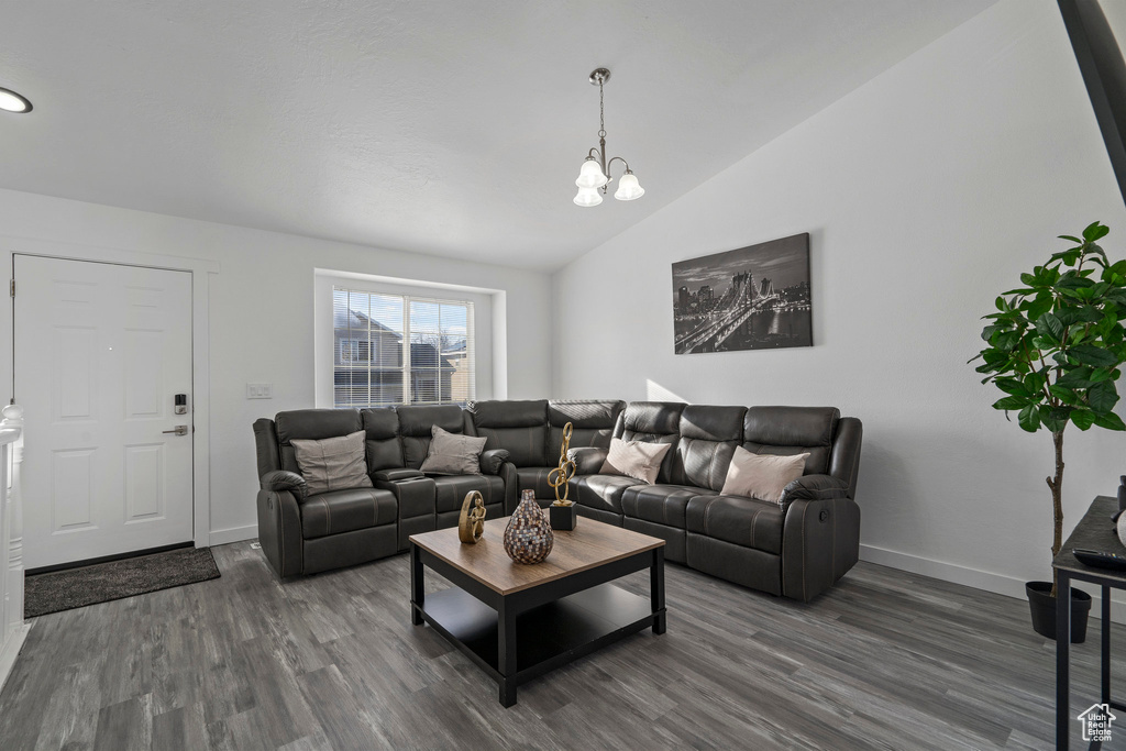 Living room featuring high vaulted ceiling, a notable chandelier, and dark wood-type flooring