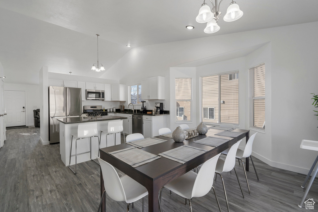 Dining area featuring high vaulted ceiling, dark hardwood / wood-style floors, sink, and a notable chandelier