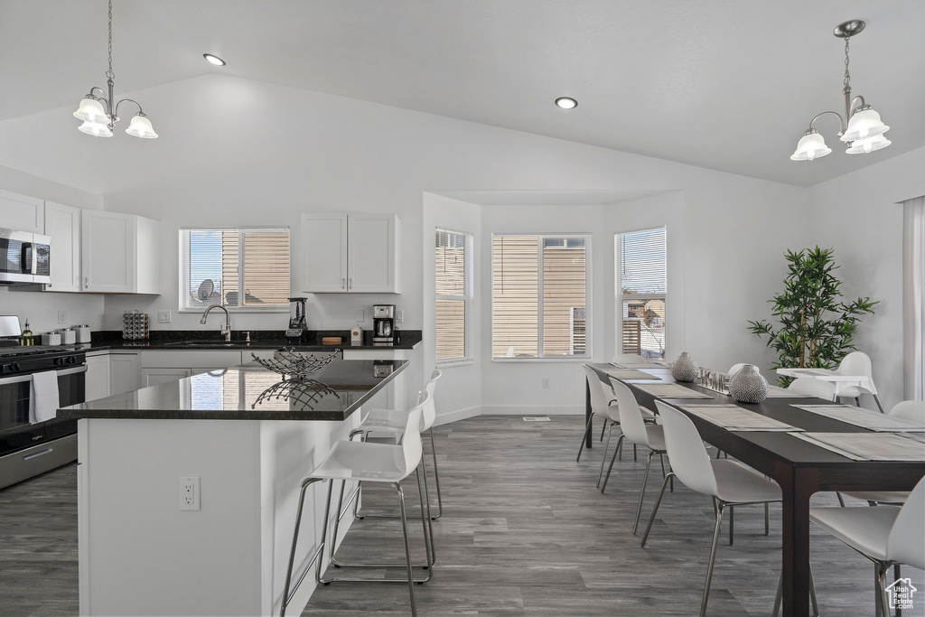 Kitchen with a center island, appliances with stainless steel finishes, white cabinets, and dark hardwood / wood-style floors