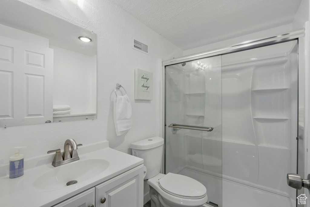 Bathroom featuring vanity with extensive cabinet space, toilet, and a textured ceiling