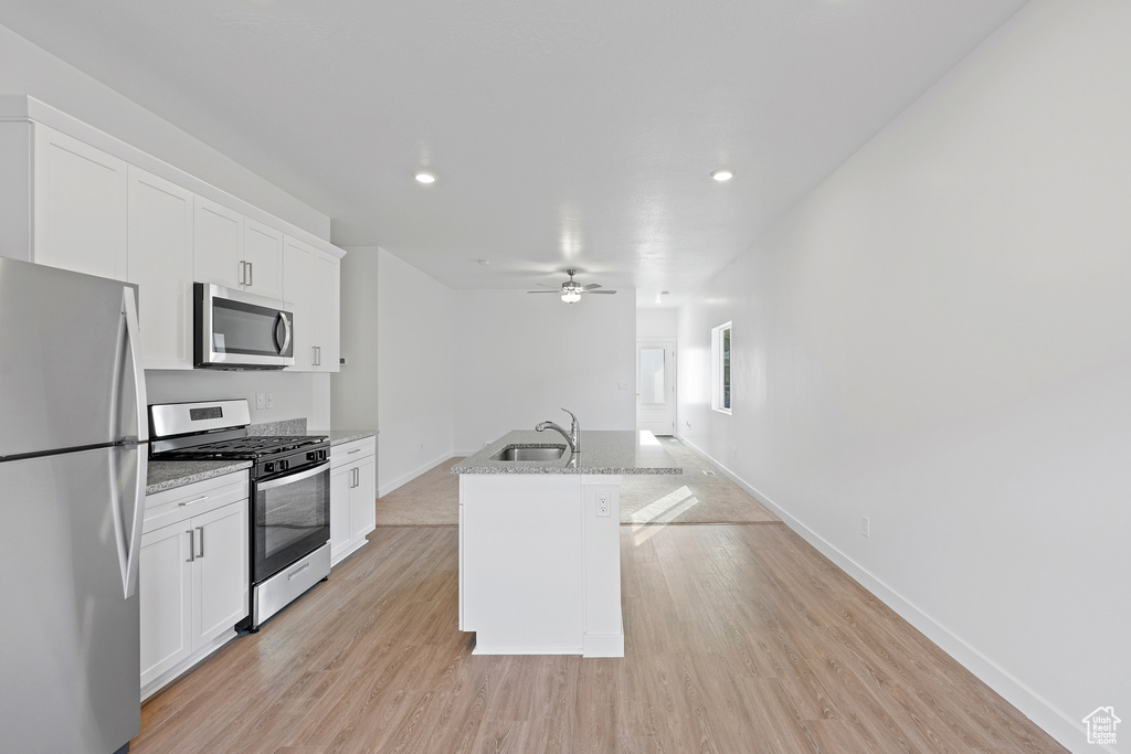 Kitchen with a center island with sink, ceiling fan, light wood-type flooring, white cabinets, and appliances with stainless steel finishes