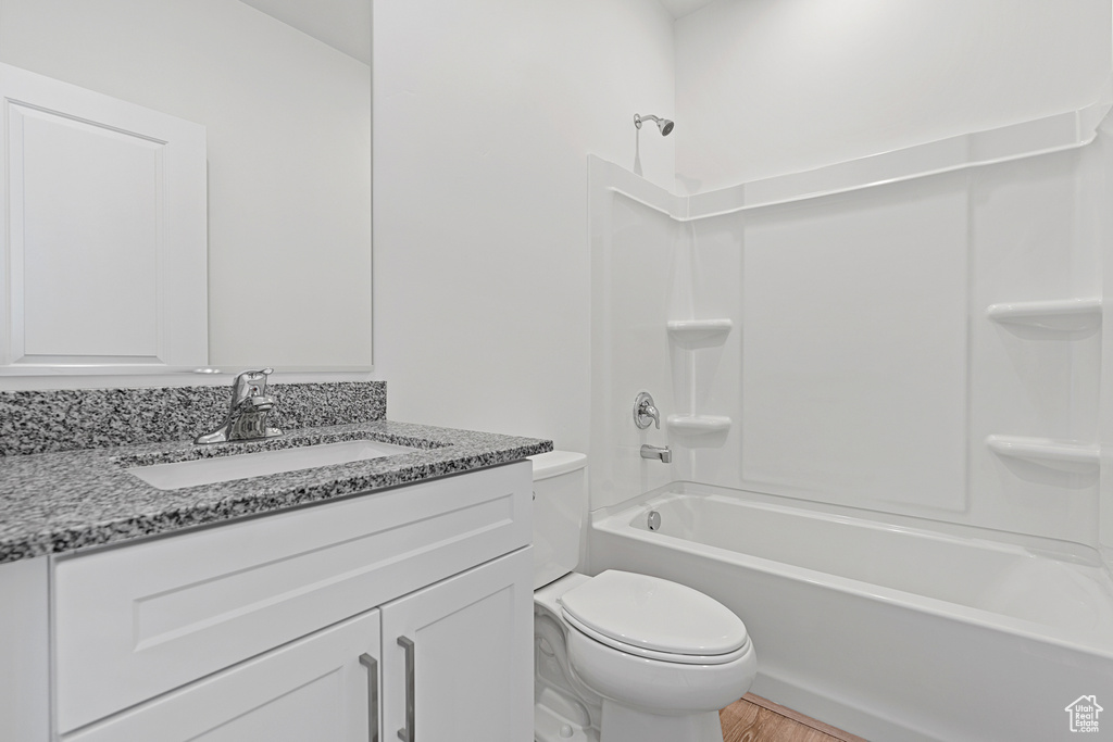 Full bathroom with hardwood / wood-style floors, toilet, shower / washtub combination, and vanity