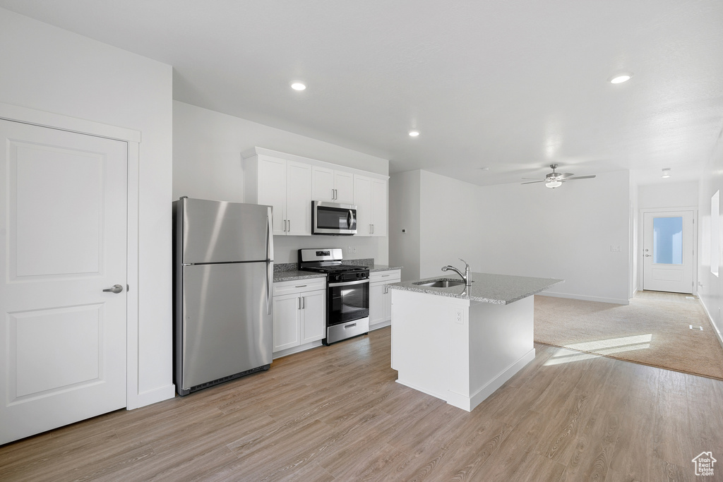 Kitchen featuring light carpet, appliances with stainless steel finishes, white cabinetry, and sink