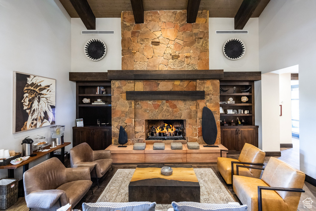 Living room featuring a towering ceiling, a fireplace, beam ceiling, wood ceiling, and wood-type flooring