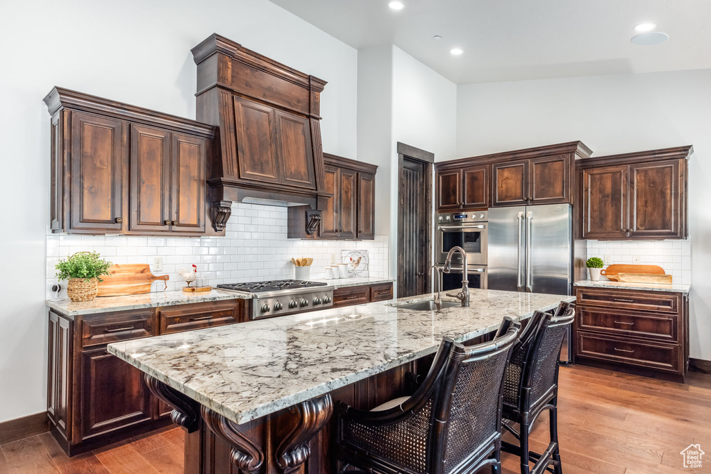 Kitchen with appliances with stainless steel finishes, sink, tasteful backsplash, and a kitchen island with sink