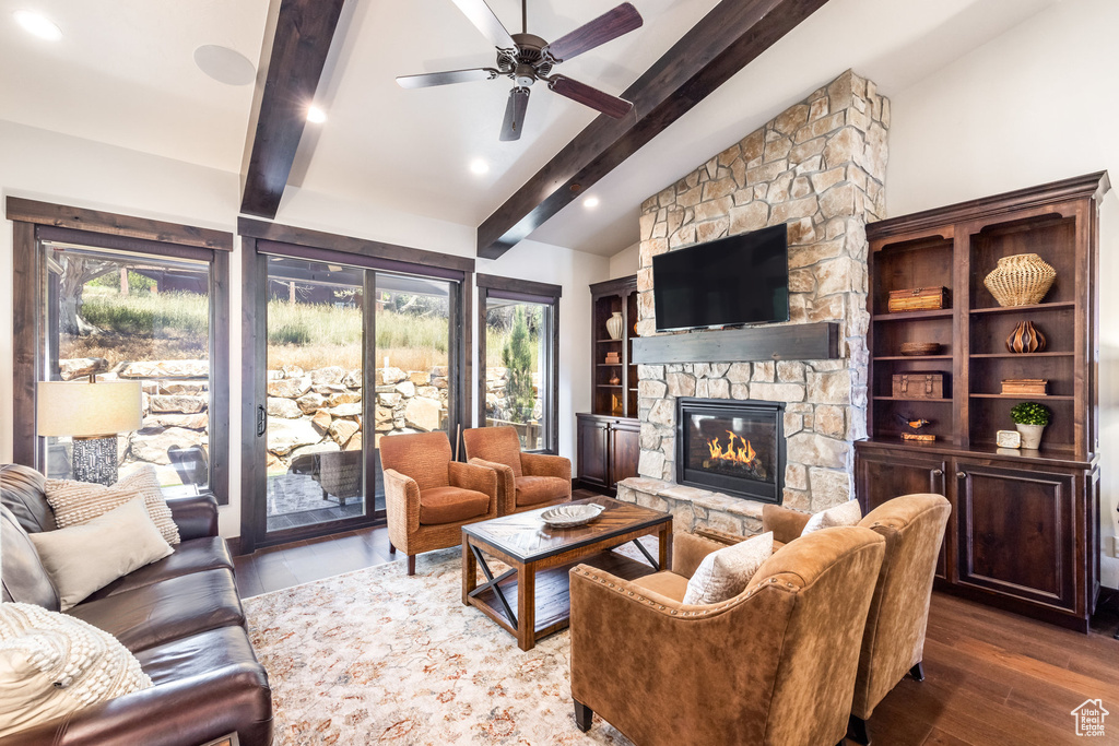 Living room with a stone fireplace, ceiling fan, dark hardwood / wood-style flooring, and a wealth of natural light