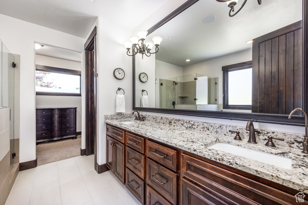 Bathroom featuring a healthy amount of sunlight, tile flooring, dual sinks, and vanity with extensive cabinet space