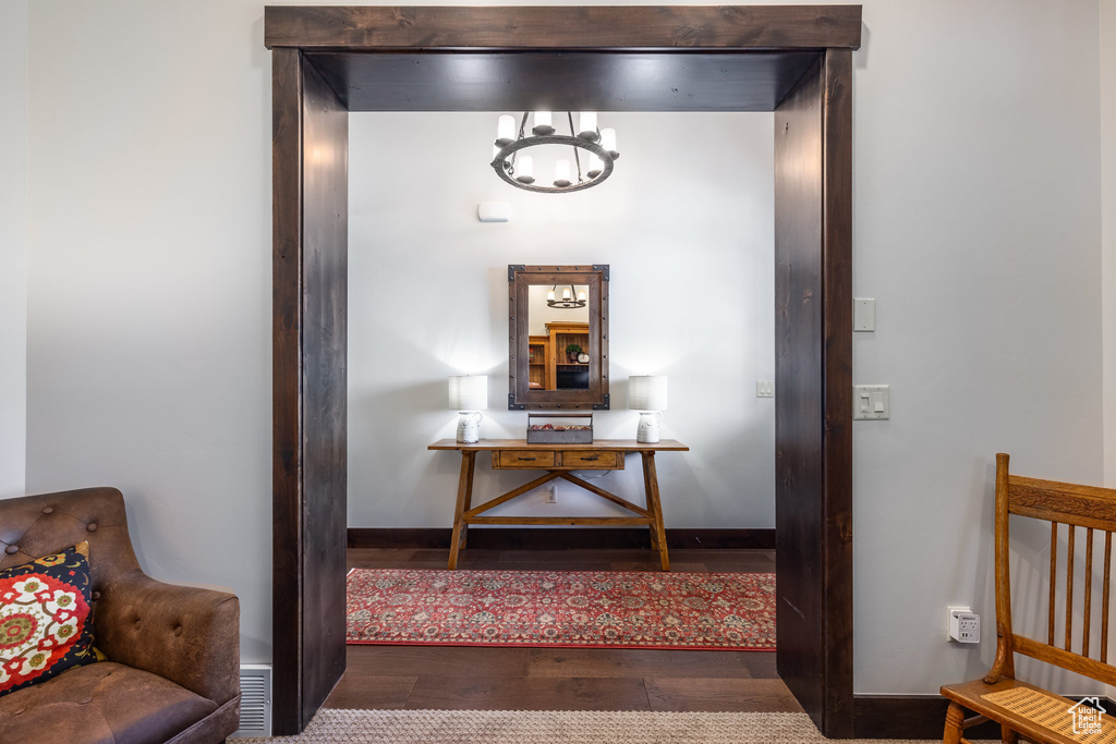 Hallway with an inviting chandelier and dark wood-type flooring