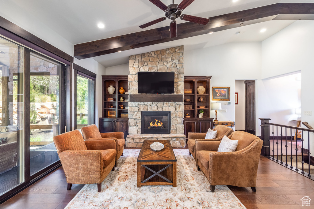 Living room featuring a fireplace, vaulted ceiling with beams, built in shelves, wood-type flooring, and ceiling fan