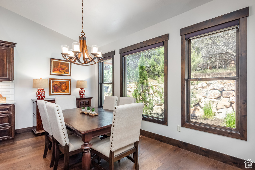 Dining area with plenty of natural light, an inviting chandelier, and dark wood-type flooring