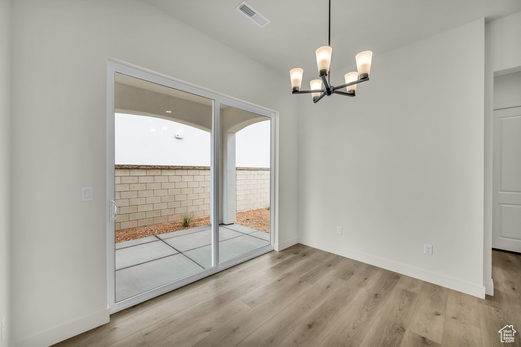 Unfurnished dining area featuring light hardwood / wood-style flooring and a chandelier