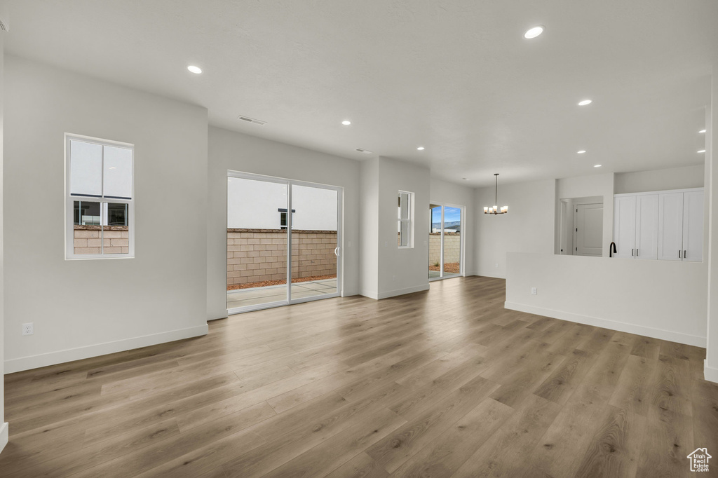 Unfurnished living room featuring light hardwood / wood-style flooring and a notable chandelier